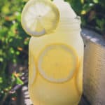 This is the category image for "summer recipes" and is a photo of a large frozen lemonade in a mason jar with sliced lemons.